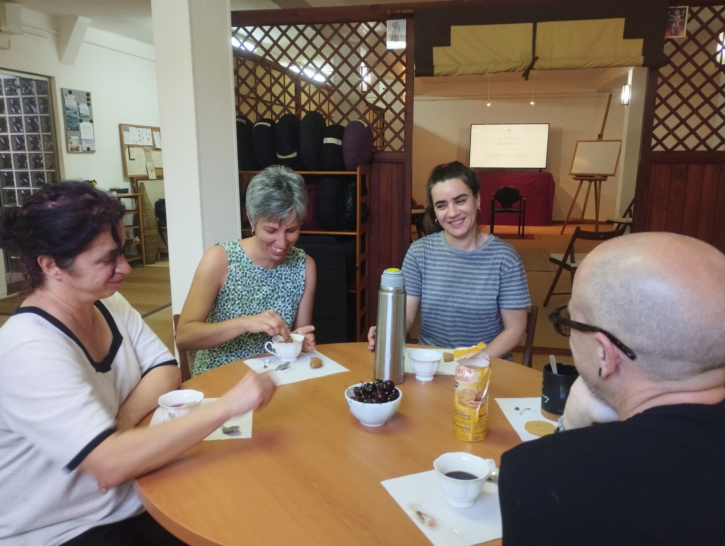 Cuatro personas comparten una conversación alrededor de una mesa.